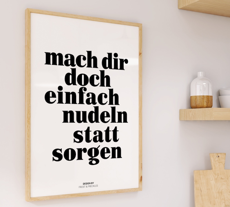 Pu&ograve; includere: Una stampa incorniciata con il testo "mach dir doch einfach nudeln statt sorgen" in lettere nere in grassetto su uno sfondo bianco. Il testo &egrave; centrato sulla stampa. La stampa &egrave; incorniciata in una cornice di legno chiaro.