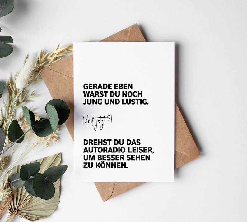 May include: A white card with black text that reads "GERADE EBEN WARST DU NOCH JUNG UND LUSTIG. Und jetzt?! DREHST DU DAS AUTORADIO LEISER, UM BESSER SEHEN ZU K&Ouml;NNEN."