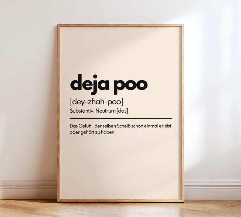 May include: A framed print with the words "deja poo" in bold black letters. Below the title is the phonetic pronunciation and the German word for noun. The definition of the phrase is written in German below.