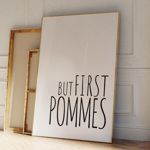 Może przedstawiać: Biały plakat w złotej ramie z napisem "But first pommes" czarnymi literami.