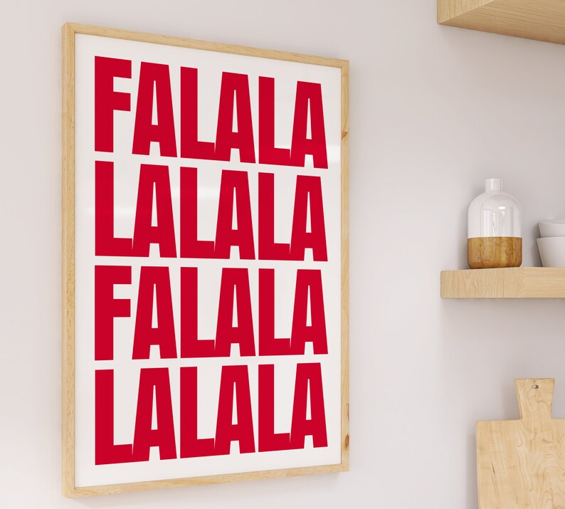 May include: A framed art print with the words "FALALA LALALA FALALA LALALA" in bold red letters on a white background. The frame is a light wood color, and the print is displayed on a white wall.