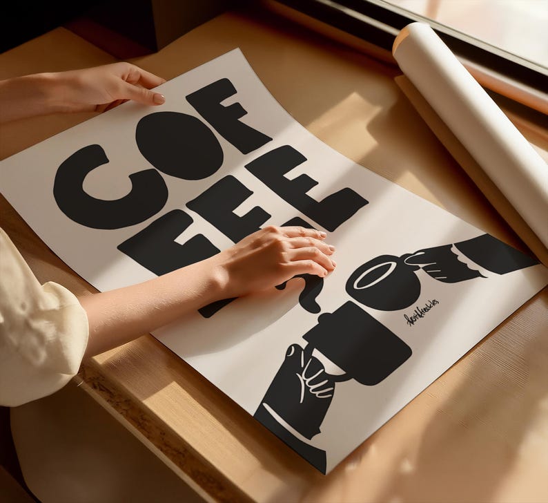 May include: A white poster with black text that reads "COFFEE" in a stylized font. The poster also features a black silhouette of a hand pouring coffee from a mug into another cup.