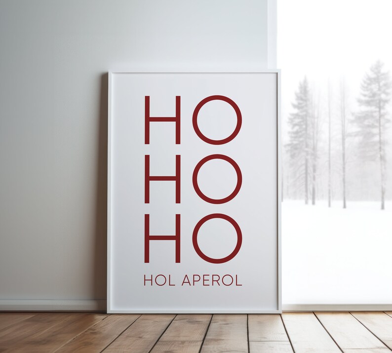 May include: A rectangular white framed wall art print featuring the dark red text HO HO HO stacked vertically, with the text HOL APEROL printed in smaller dark red capital letters underneath the main graphic on a white background.