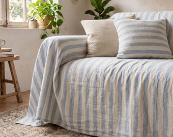 May include: A sofa covered in a light blue and off-white striped fabric throw, featuring a matching striped square throw cushion and a plain beige square throw cushion placed on the seat.