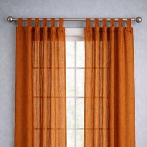 May include: A pair of burnt orange tab-top curtains hanging from a silver rod. The sheer fabric allows light to filter through, revealing a window with white trim and a view to the outside. The curtains are floor-length.