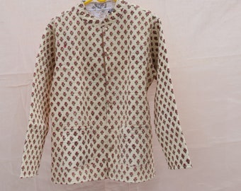 Puede incluir: Una camisa de manga larga de color crema con estampado floral en tonos rojos y verdes. La camisa tiene un cuello mandarín y cierre de botones en la parte delantera.