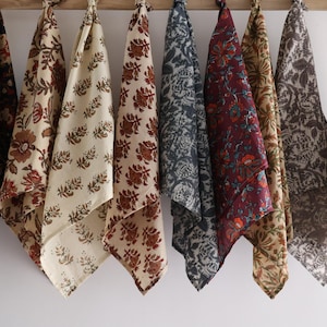 May include: A collection of eight fabric squares with various floral patterns. The squares are in shades of brown, red, blue, and white.