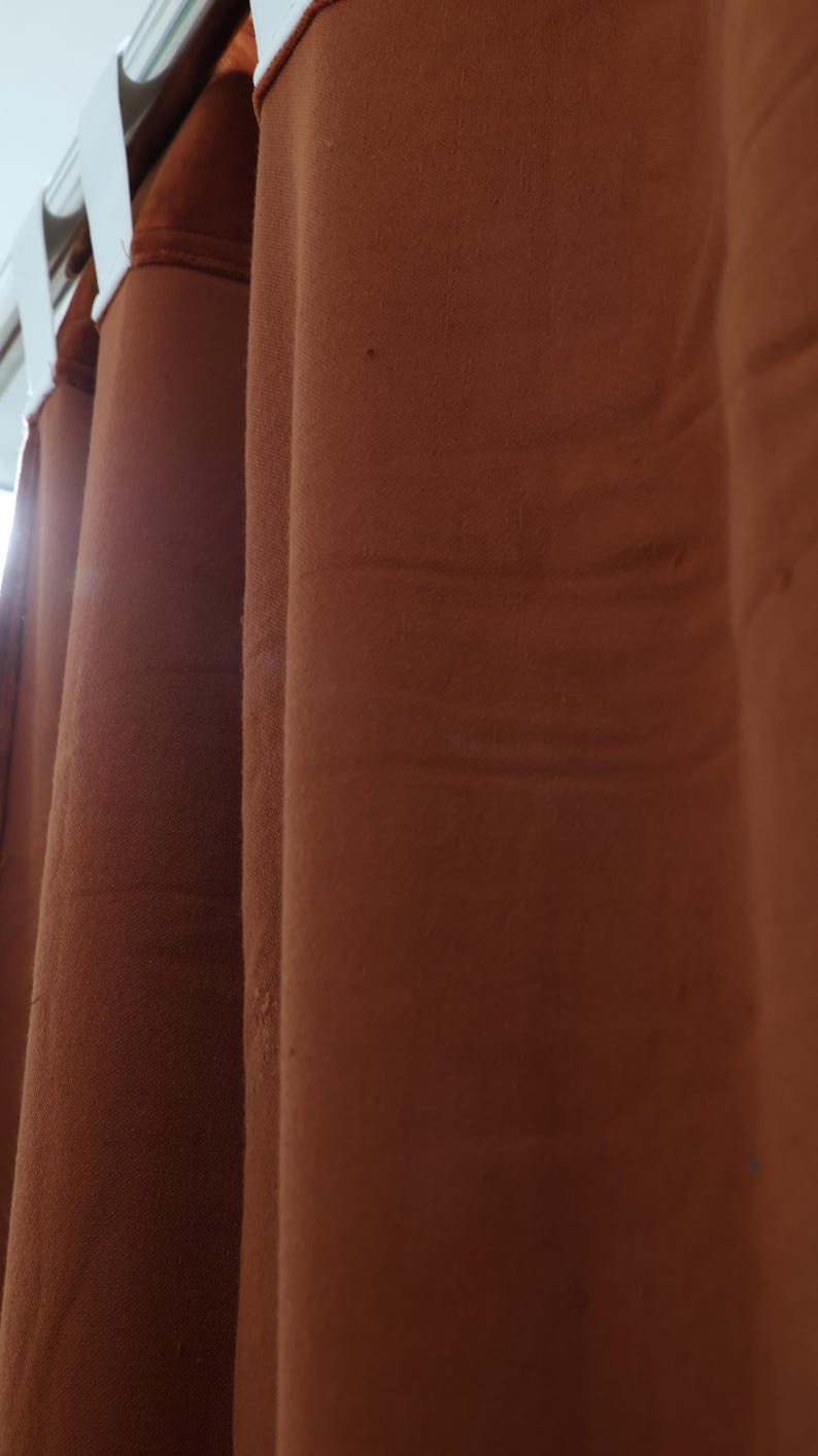 May include: Three brown velvet curtains hanging from a white curtain rod.