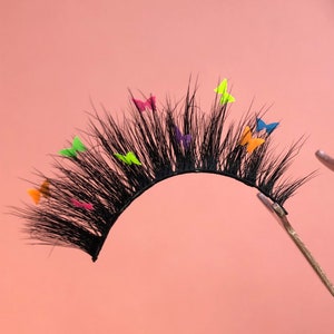 May include: A white ceramic mug with a black handle and the text "But First, Coffee" in a bold, black font. The mug is set against a blurred background, suggesting a cosy setting.