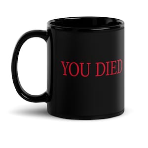 Könnte beinhalten: Schwarze Keramik-Kaffeetasse mit roter Aufschrift "YOU DIED".
