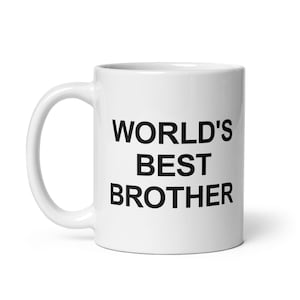 May include: A white ceramic mug with the text "WORLD'S BEST BROTHER" in black, bold letters. The mug has a curved handle and a cylindrical shape, suitable for hot or cold beverages.