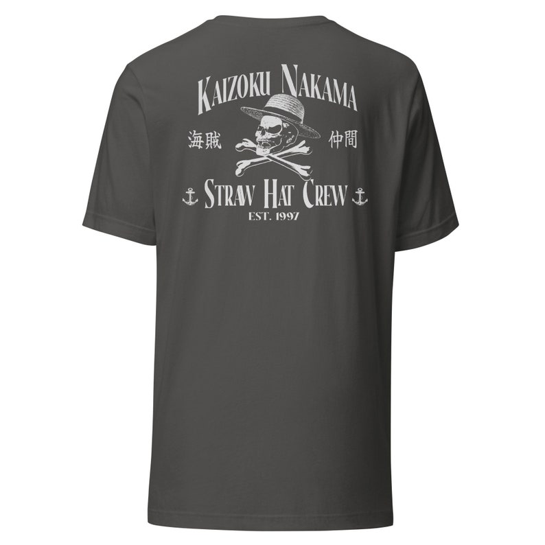Pode incluir: Uma camiseta cinza escura com uma estampa branca de uma caveira usando um chap&eacute;u de palha e ossos cruzados. O texto "Kaizoku Nakama" est&aacute; acima da caveira, e o texto "Straw Hat Crew" est&aacute; abaixo da caveira. O texto "EST. 1997" est&aacute; abaixo do nome da tripula&ccedil;&atilde;o.
