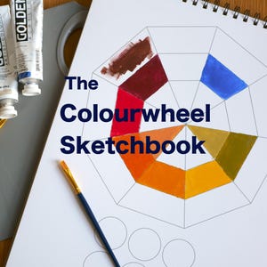 Könnte beinhalten: Ein Farbrad-Skizzenbuch mit Spiralbindung, Farbtuben und Pinseln. Das Skizzenbuch zeigt ein Farbrad mit verschiedenen Farben. Farbtuben sind weiß mit goldfarbenen Buchstaben. Eine graue Palette enthält Farbtupfer.