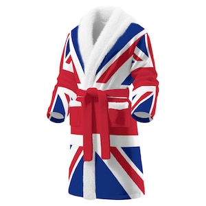 May include: A plush, full-length robe featuring the Union Jack flag design in red, white, and blue. The robe has a white, fluffy shawl collar, cuffs, and pockets. A matching red belt cinches the waist.
