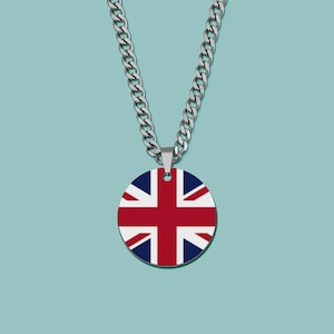 Könnte beinhalten: Eine silberfarbene Halskette mit einem runden Anhänger, der das Union Jack-Flaggen-Design zeigt. Der Anhänger hat ein rotes Kreuz und weiße und rote diagonale Streifen auf marineblauem Hintergrund. Die Halskette hängt vor einem hellblauen Hintergrund.