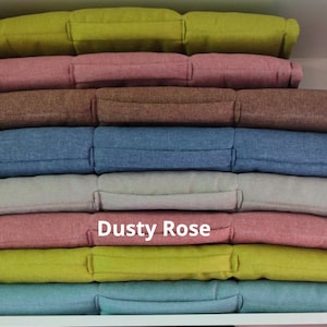 Peut inclure: Une pile de dix housses de coussin dans diff&eacute;rentes couleurs, dont rose poudr&eacute;, vert, bleu et gris. Les coussins sont faits d'un tissu doux et textur&eacute; et ont une forme rectangulaire simple.