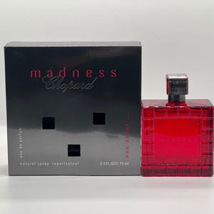 May include: A red square perfume bottle and a black box with the text "madness Chopard". The bottle has a silver cap and the box has the text "eau de parfum" and "natural spray-vaporisateur". The bottle contains 75 ml of perfume.