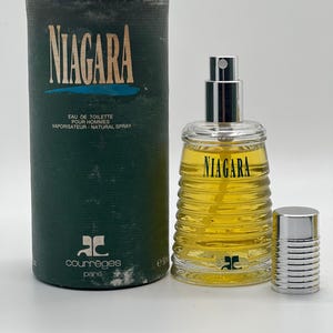 May include: A vintage bottle of Courr&egrave;ges Niagara Eau de Toilette for men. The cylindrical green box and glass bottle feature the name "NIAGARA" in large letters. The bottle is filled with a yellow liquid and has a silver cap.