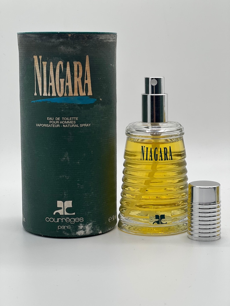 May include: A vintage bottle of Courr&egrave;ges Niagara Eau de Toilette for men. The cylindrical green box and glass bottle feature the name "NIAGARA" in large letters. The bottle is filled with a yellow liquid and has a silver cap.