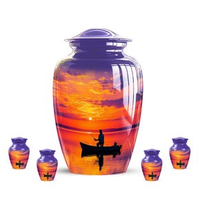 May include: A large, purple cremation urn and five smaller keepsake urns. The urns feature a sunset scene with a person fishing in a boat. The sunset is reflected in the water. The smaller urns have a cross and boat design.