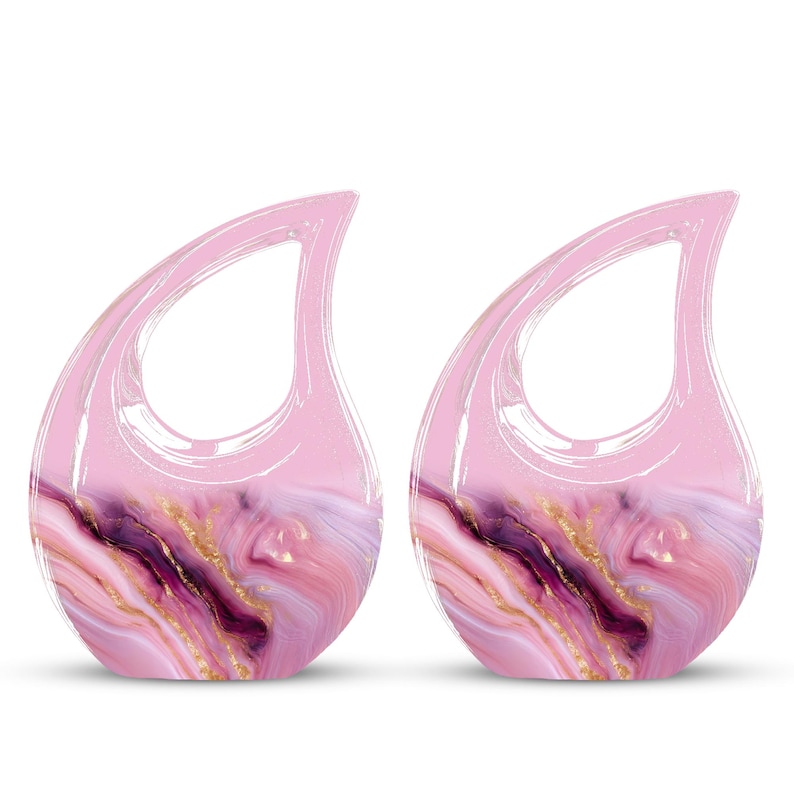 May include: Two pink teardrop-shaped decorative items with a marbled design. The marble pattern features shades of pink, purple, and gold. The top portion of each item is a solid, translucent pink, and they have a loop at the top.