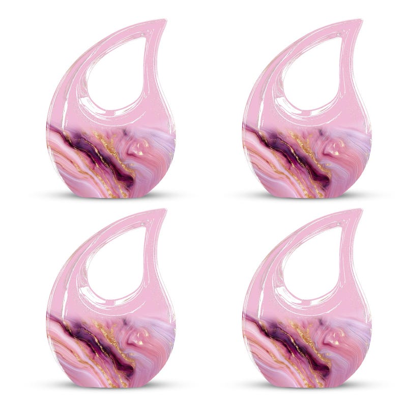 May include: Four teardrop-shaped decorative objects with a handle. The objects have a pink, translucent handle and a marbled design in shades of pink, purple, and gold. The objects are arranged in a square formation.