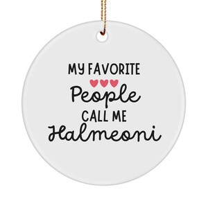 May include: A white, round ceramic ornament with the text "MY FAVORITE People CALL ME Halmeoni" in black script. Three pink hearts are above the word "People". A gold string is attached for hanging.
