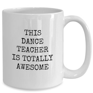 May include: White ceramic coffee mug with black text that reads "This Dance Teacher Is Totally Awesome".