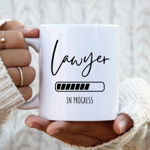 May include: White ceramic mug with black text that reads "Lawyer" and a progress bar that says "In Progress".