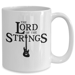 May include: White ceramic mug with a black graphic of an electric guitar and the text "The Lord of the Strings".