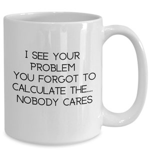 May include: White ceramic mug with a curved handle. The mug features black text that reads: "I SEE YOUR PROBLEM YOU FORGOT TO CALCULATE THE.... NOBODY CARES."