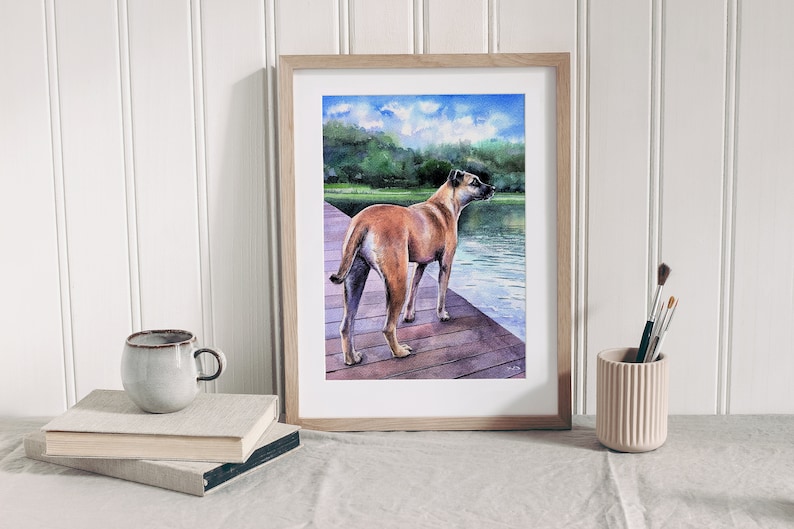 Puede incluir: Una pintura de acuarela de un perro marr&oacute;n de pie en un muelle de madera con vistas a un lago. El perro mira hacia la derecha de la imagen, y el agua es de color azul claro. El cielo es de color azul claro con nubes blancas.