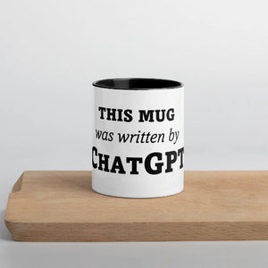May include: White ceramic mug with a black rim. The mug has black text that reads "THIS MUG was written by CHATGPT".