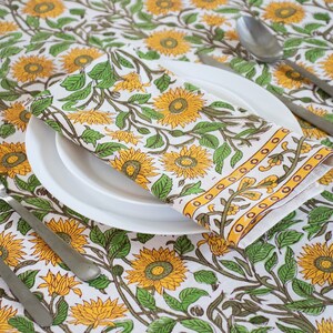 cotton floral Mustard block print tablecloth in Sunflowers design with single napkin displayed on a white porcelain plate. This makes a perfect mothers day gift.