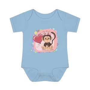Könnte beinhalten: Ein hellblauer Baby-Strampler mit einer rosa-weißen Schleife, einem braunen Affen, der einen roten Herzluftballon hält, und rosa Blumen auf rosa Hintergrund.