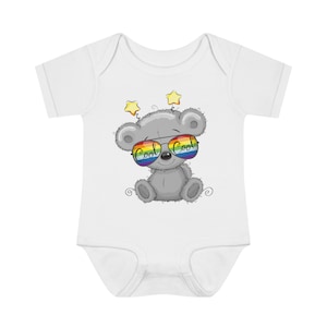 Könnte beinhalten: Ein weißer Baby-Strampler mit einem grauen Teddybär, der eine Regenbogen-Sonnenbrille trägt, auf der "Cool Cool" steht. Der Teddybär hat zwei gelbe Sterne über seinem Kopf.