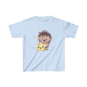 May include: A light blue t-shirt with a cartoon hedgehog holding a yellow star. The hedgehog has brown fur, a blue nose, and a happy expression. The star has a smiling face.