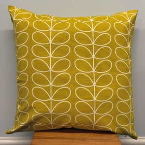 May include: Square decorative pillow with a mustard yellow background and a white leaf pattern. The pillow is made of fabric and has a zipper closure. The pillow is approximately 18 inches square.