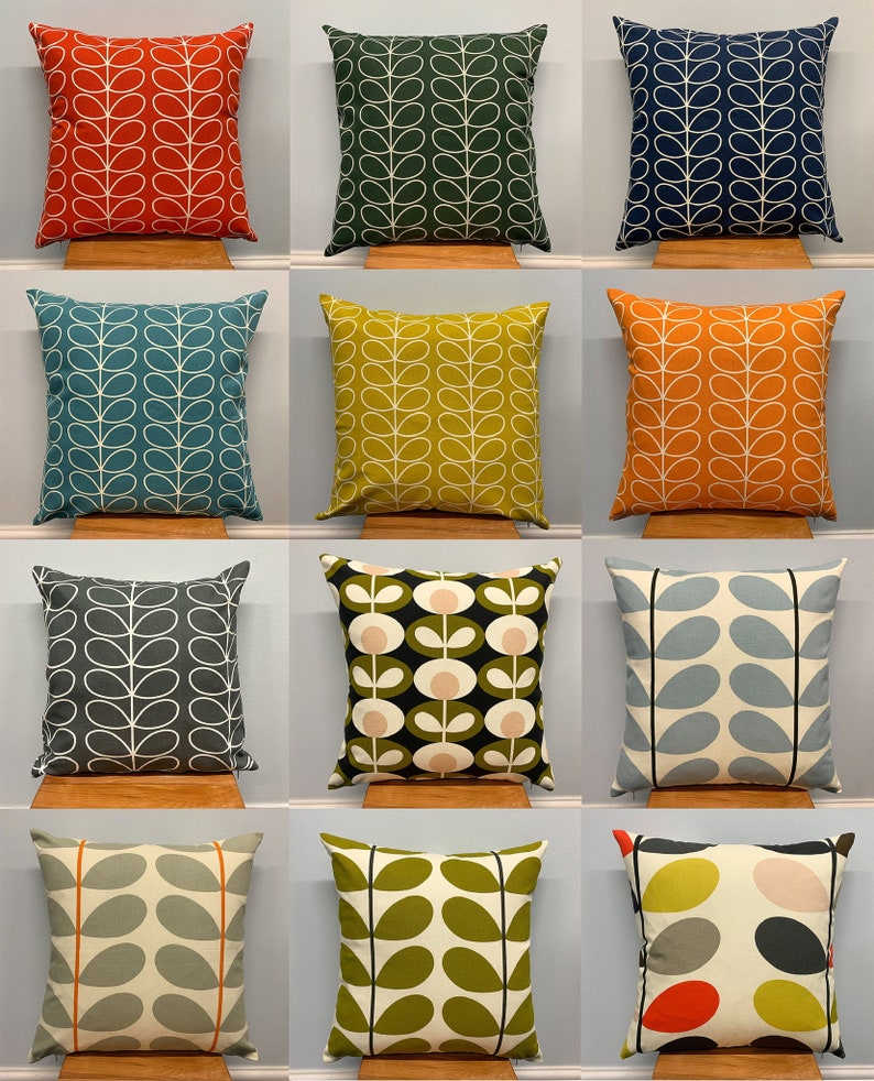 May include: A collection of decorative throw pillows in various colors, each featuring a white leaf pattern. Colors include red, green, blue, teal, yellow, orange, gray, black, light blue, and olive green. The pillows are square and rest on wooden stands.