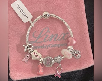Bracelet Linx avec breloques roses sur le thème de la sensibilisation au cancer du sein