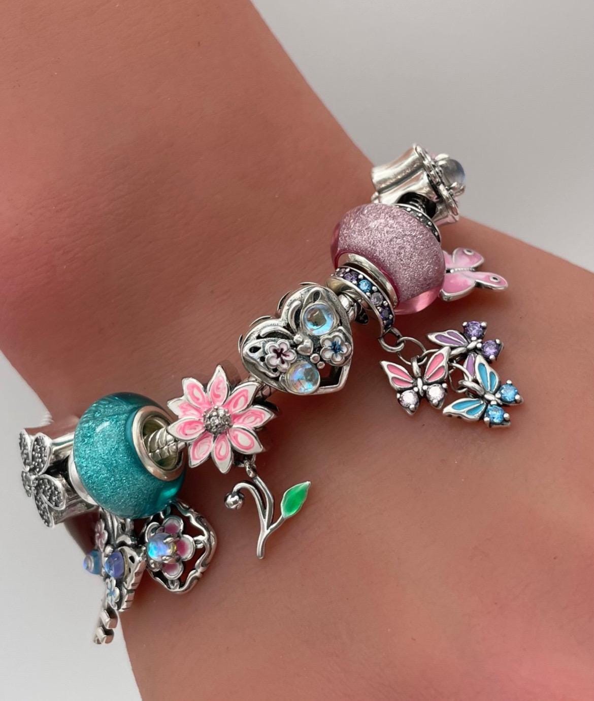 ピンクとターコイズの蝶と花をテーマにしたチャームが付いたパンドラ