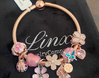 Pulsera de cadena tipo serpiente en oro rosa con dijes temáticos de color rosa de Linx