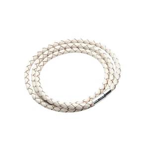 May include: A white braided leather bracelet with a silver magnetic clasp. The bracelet is made of multiple strands of leather woven together. The bracelet is shown on a white background.