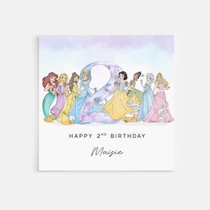 Peut inclure: Une carte d'anniversaire carrée avec un grand chiffre 2 à l'aquarelle entouré de huit princesses illustrées en robes colorées. Le texte indique HAPPY 2ND BIRTHDAY et le prénom Maisie en police cursive sous les princesses.