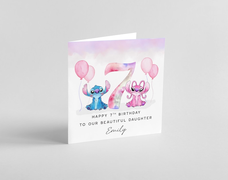 Peut inclure: Carte d'anniversaire pli&eacute;e avec un design aquarelle. La carte pr&eacute;sente un personnage de dessin anim&eacute; bleu et rose, des ballons roses et le chiffre 7. Le texte indique "Happy 7th Birthday To Our Beautiful Daughter Emily."