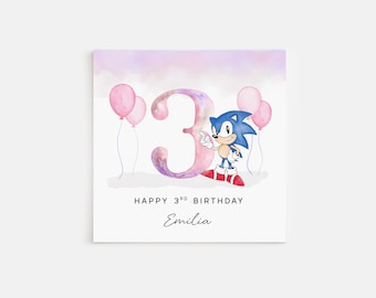 May include: A pink and purple watercolor birthday card with a large number 3 and a cartoon Sonic the Hedgehog character. The card says "Happy 3rd Birthday Emelia".