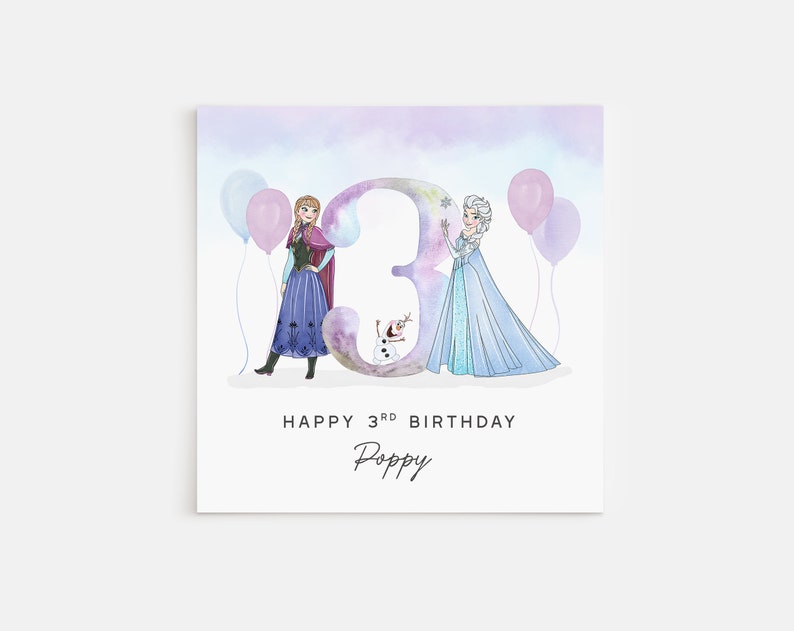 Puede incluir: Una tarjeta de cumplea&ntilde;os con una ilustraci&oacute;n de acuarela de Elsa y Anna de Frozen, de pie frente a un gran n&uacute;mero 3. La tarjeta tiene un fondo azul claro con globos rosas y morados. El texto "Happy 3rd Birthday Poppy" est&aacute; impreso debajo de la ilustraci&oacute;n.