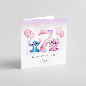 Peut inclure: Carte de v&oelig;ux blanche pli&eacute;e avec un motif aquarelle. La carte pr&eacute;sente un personnage de dessin anim&eacute; bleu et rose, des ballons roses et le chiffre 7. Le texte indique "HAPPY 7TH BIRTHDAY" et un nom en &eacute;criture manuscrite.