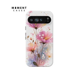 May include: White phone case with a watercolor floral design featuring pink and peach flowers. The case has a camera cutout and the text "MOMENT CASES" in black.