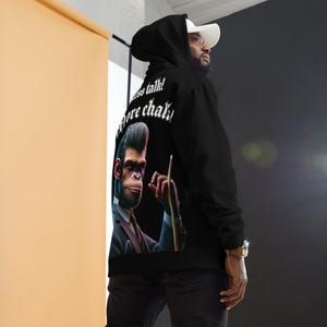 May include: Black hoodie featuring a graphic of a cartoon ape in a suit holding a pool cue. The text "Less talk! More chalk!" is printed on the hoodie.